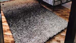 Ein Zimmer mit einem Bett, einem großen Teppich und zwei Fenstern.