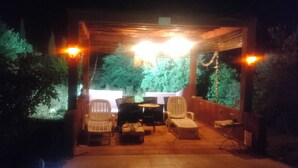 Ein Patio mit Pergola, Sitzgelegenheiten und Blick auf Grünflächen.