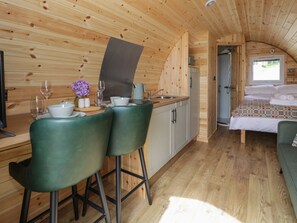 A wooden interior with a kitchen, dining area, and a bedroom with a bed and window. - Pod 1, Llanegryn near Tywyn, Gwynedd. (Tywyn)