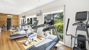 A modern gym with multiple treadmills, exercise bikes, and a large window with a view of greenery. - Seabush Retreat - Phillip Island - Resort Facilities (Cowes)