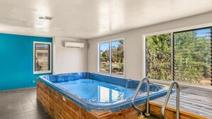 A hot tub in a room with a blue wall, a window, and a view of trees. - Seabush Retreat - Phillip Island - Resort Facilities (Cowes)