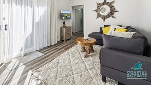 A living room with a grey sofa, a wooden coffee table, a white fluffy rug, a wooden cabinet, and a TV on the wall. - Seabush Retreat - Phillip Island - Resort Facilities (Cowes)