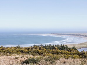 A coastal landscape with a beach, vegetation, and a clear sky. - Cabin 1 Machaire Rabhartaigh (Gortahork)
