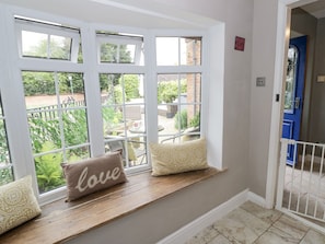 A room with a window seat, a blue door, and a view of a garden.