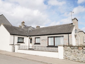 A two-story stone house with a sloped roof, a chimney, and a small porch with a metal railing. - Dalnahaven: Your Dog-Friendly Retreat (Grantown-on-Spey)