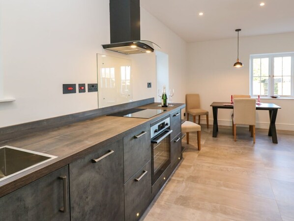 A modern kitchen with a central island, built-in oven, and a dining area with a table and chairs.