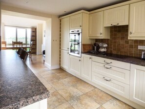 A kitchen with white cabinets, a granite countertop, and a view to the outside. - The Cart Shed Retreat in York (York)