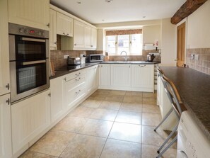 A kitchen with white cabinets, a double oven, a microwave, and a sink. - The Cart Shed Retreat in York (York)