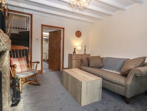 A cozy living room with a rocking chair, a sofa, a wooden coffee table, and a staircase leading to another room.