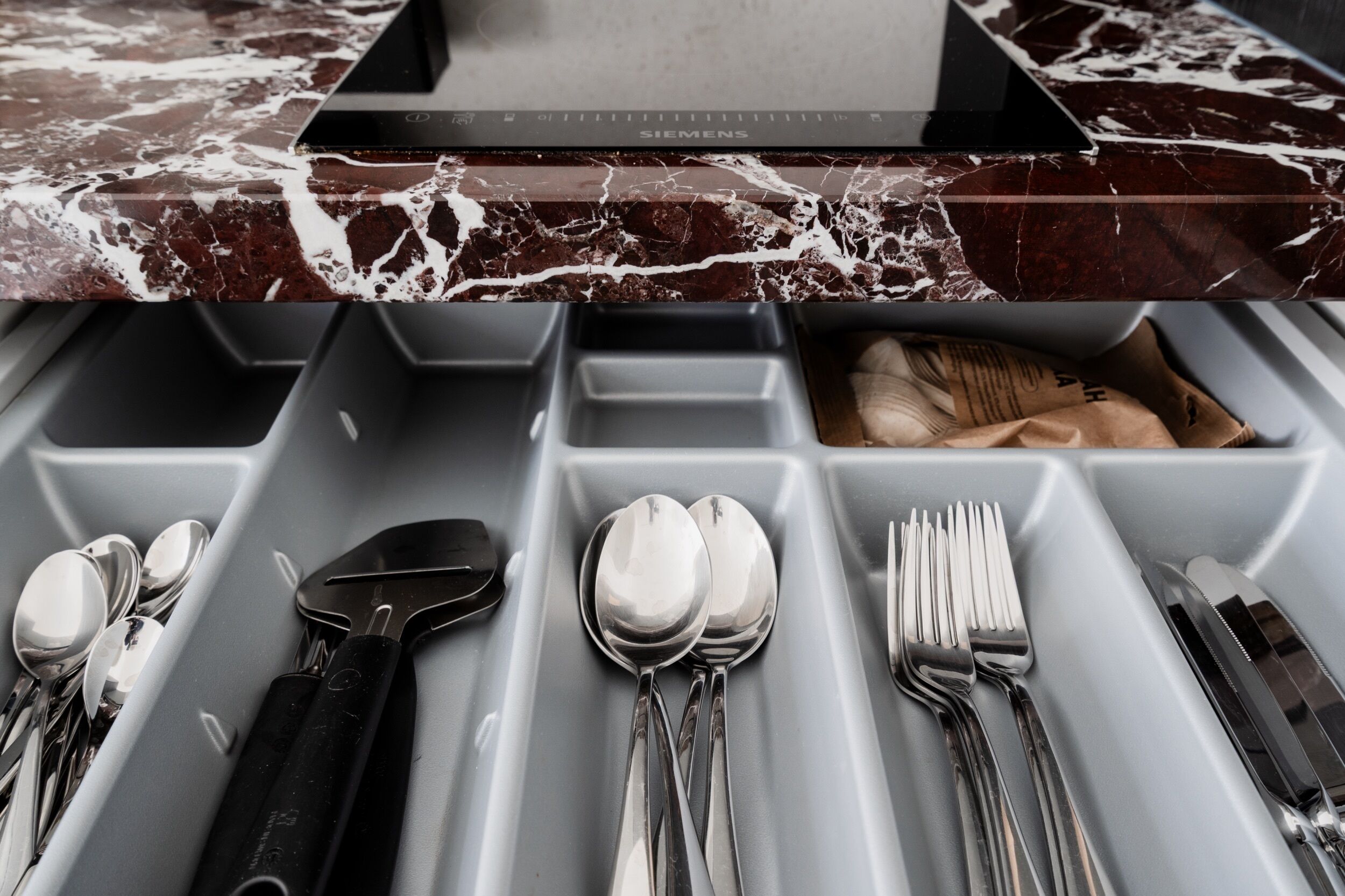 A drawer with utensils including spoons, forks, and knives.