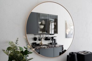 A kitchen with a round mirror, a coffee machine, and a toaster. - Modern Luxury Flat - Steps to Station (Helsinki)