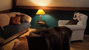 Una habitación acogedora con sofá, sillón, lámpara y techo de vigas de madera.