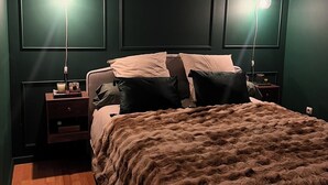 Un dormitorio con una cama grande, dos lámparas de noche, una mesita de noche y suelo de madera.