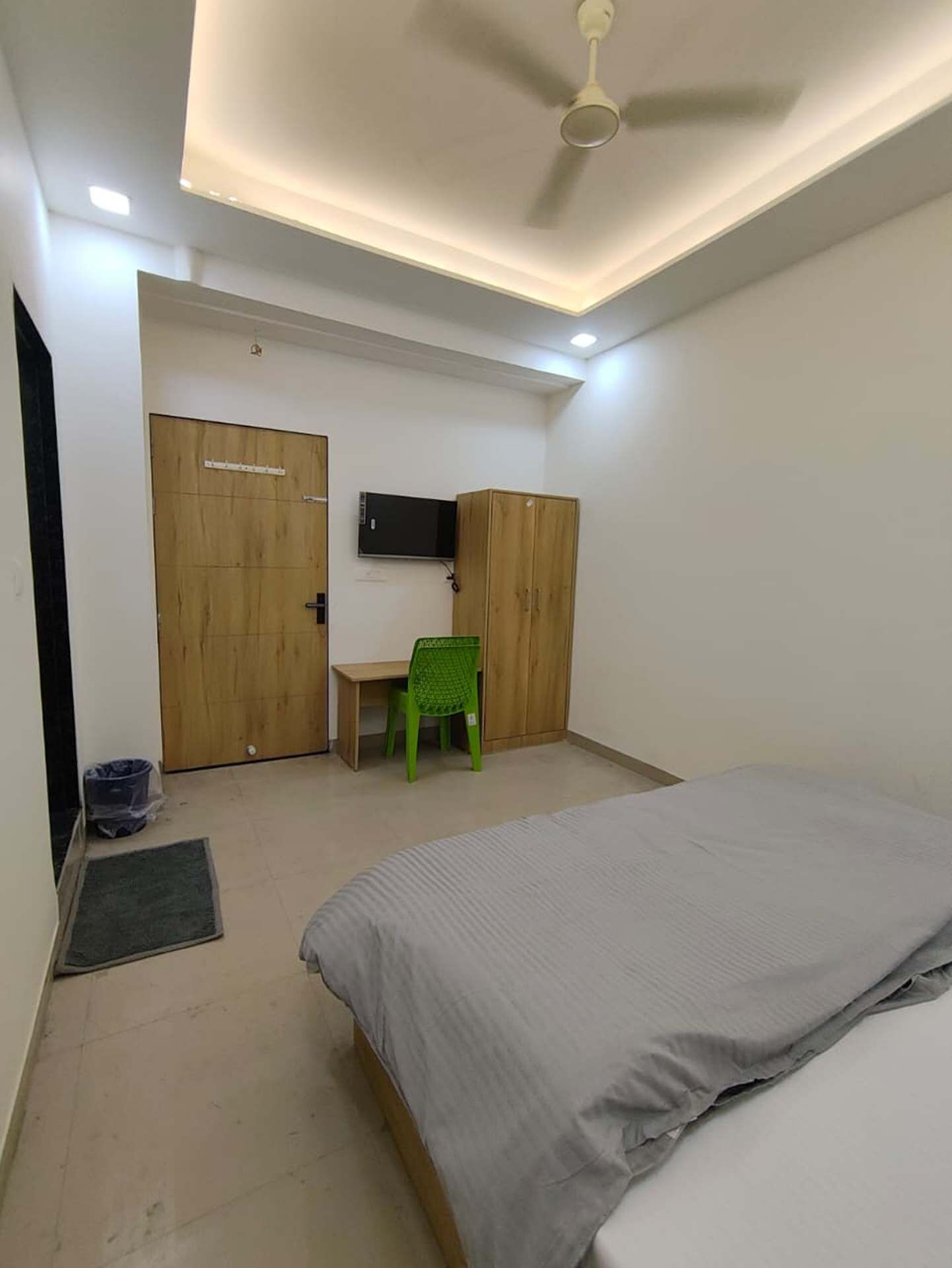 Ein Schlafzimmer mit Bett, Schreibtisch, Stuhl, Fernseher und Kleiderschrank.