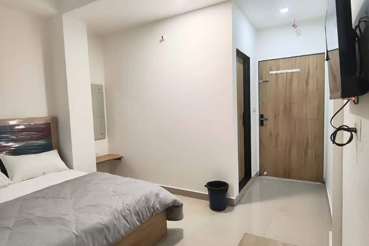 A modern bedroom with a bed, a TV mounted on the wall, and a wooden door.
