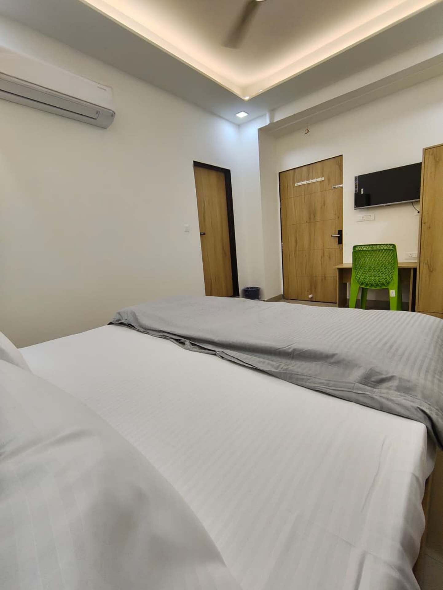 Une chambre avec deux lits, un bureau, une chaise, une télévision et une porte.