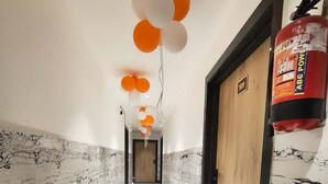 Un corridoio con pareti in marmo, una porta in legno e un estintore.