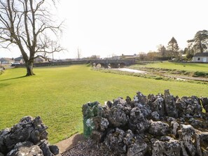 A stone bridge over a river, a grassy field, and a stone wall in the foreground. - Cherry Tree Cottage, Soulby (Kirkby Stephen)