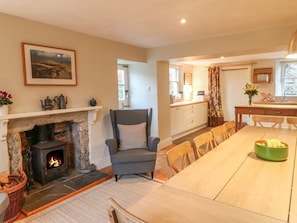 A living room with a fireplace, a dining area, and a kitchen.