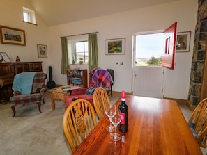 A dining area with a wooden table, chairs, a bottle of wine, and wine glasses.