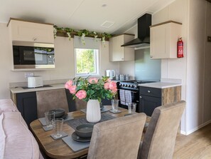 Una cocina moderna con comedor, que incluye estufa, microondas y un florero con flores sobre la mesa.