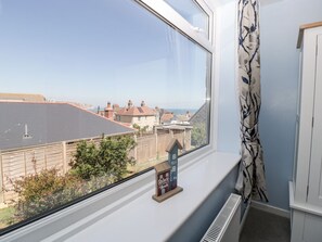 A window with a view of a residential area, a small house-shaped decoration, and a radiator.