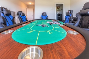Una mesa de dados con cuatro sillas, una superficie de fieltro verde y fichas de póker.