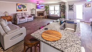 A modern living room with a fireplace, a television, and a dining area with granite countertops. - Hideaway Getaway - Statham (Statham)