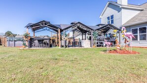 A house with a covered outdoor area, a barbecue grill, and a pink flamingo statue. - Hideaway Getaway - Statham (Statham)