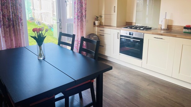 Une cuisine équipée d’une table à manger, de chaises, d’une cuisinière et d’un four, et offrant une vue sur l’extérieur.