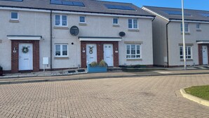 Une rangée d’immeubles d’appartements modernes, dotés de panneaux solaires, de portes numérotées et d’antennes paraboliques.