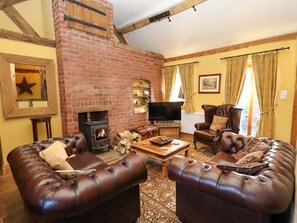Una sala de estar acogedora con sofás de cuero, chimenea, televisor y pared de ladrillo.