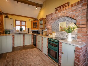 Una cocina con chimenea de ladrillo, armarios de madera y salpicadero de azulejos.