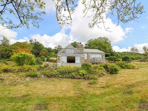 Une maison avec une façade en pierre, un balcon et un jardin.