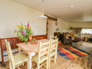 A dining area with a wooden table, chairs, and a floral centerpiece. - Buzzards Breg, Builth Wells (Builth Wells)