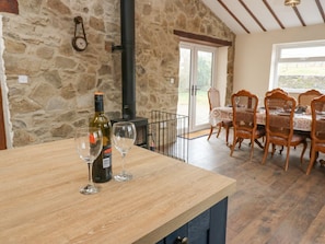 A stone wall, a wooden counter with wine bottles and glasses, a dining area with chairs and a table, and a chimney. - Parkers House, Alston (Alston)