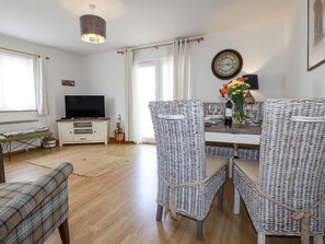 A dining area with wicker chairs, a table, a television, and a clock on the wall. - Flat 4, Newquay, Cornwall (Newquay)
