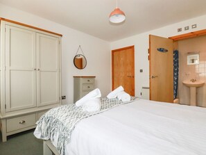 A bedroom with a bed, a wardrobe, a mirror, a bathroom with a sink and shower, and a hanging light fixture. - Flat 4, Newquay, Cornwall (Newquay)