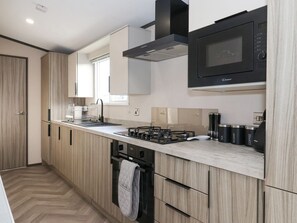 Una cucina moderna con mobili in legno, un forno a microonde, un fornello a gas e una lavastoviglie.