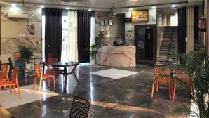Un vestíbulo con mostrador de recepción, zona de estar y escalera.