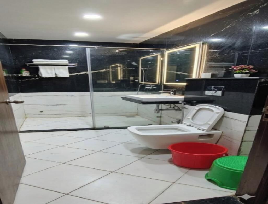 A bathroom with a glass-enclosed shower, a white toilet, a sink, and a mirror.