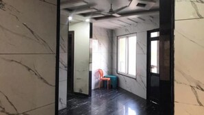 Un pasillo con paredes de mármol y piso negro que conduce a una habitación con ventana y sillón.
