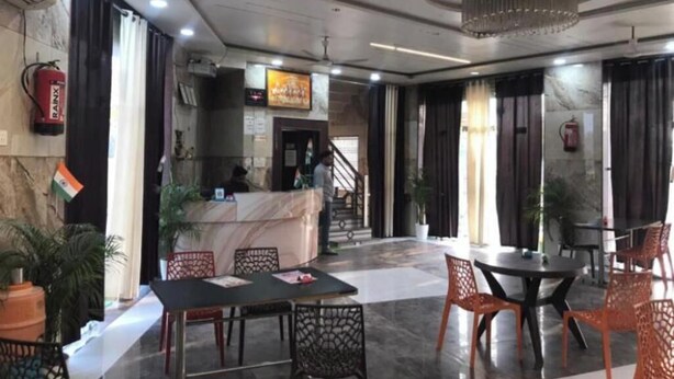 Un vestíbulo de hotel con una recepción, zona de estar y una escalera que conduce a los pisos superiores.