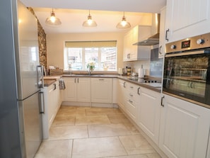 A kitchen with white cabinets, a stainless steel refrigerator, a built-in oven, and a window with a view.