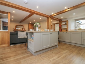 A modern kitchen with wooden beams, a central island, and a grey cabinet. - Lime Tree Cottage, in Cumbria. (Kirkby Stephen)