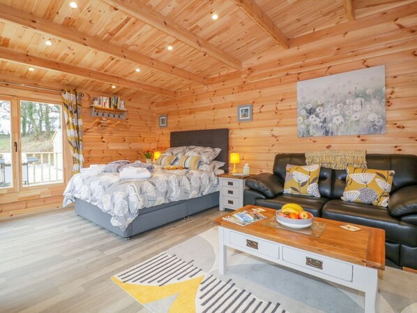 Ein Holzhütten-Interieur mit einem Bett, einem Sofa, einem Couchtisch und einem Bild an der Wand.