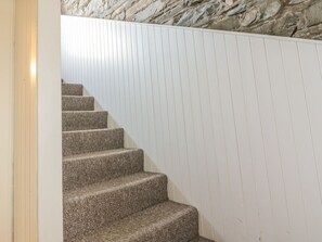 Eine Treppe mit steinernen Stufen, die zu einer weißen Wand mit vertikalen Linien führt.