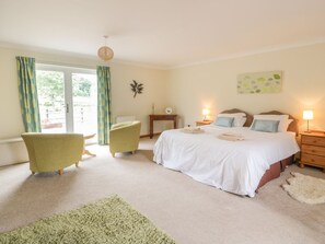 Une chambre à coucher avec un lit, deux tables de chevet, une chaise, une petite table et un tapis vert.