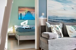 A bedroom with a bed, a nightstand, a dresser, and a wall with a sunset painting.