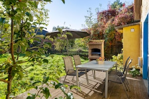An outdoor patio with a barbecue grill, a table, and chairs.